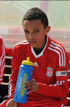 Trent Alexander-Arnold as a kid holding a water bottle in Liverpool uniform.